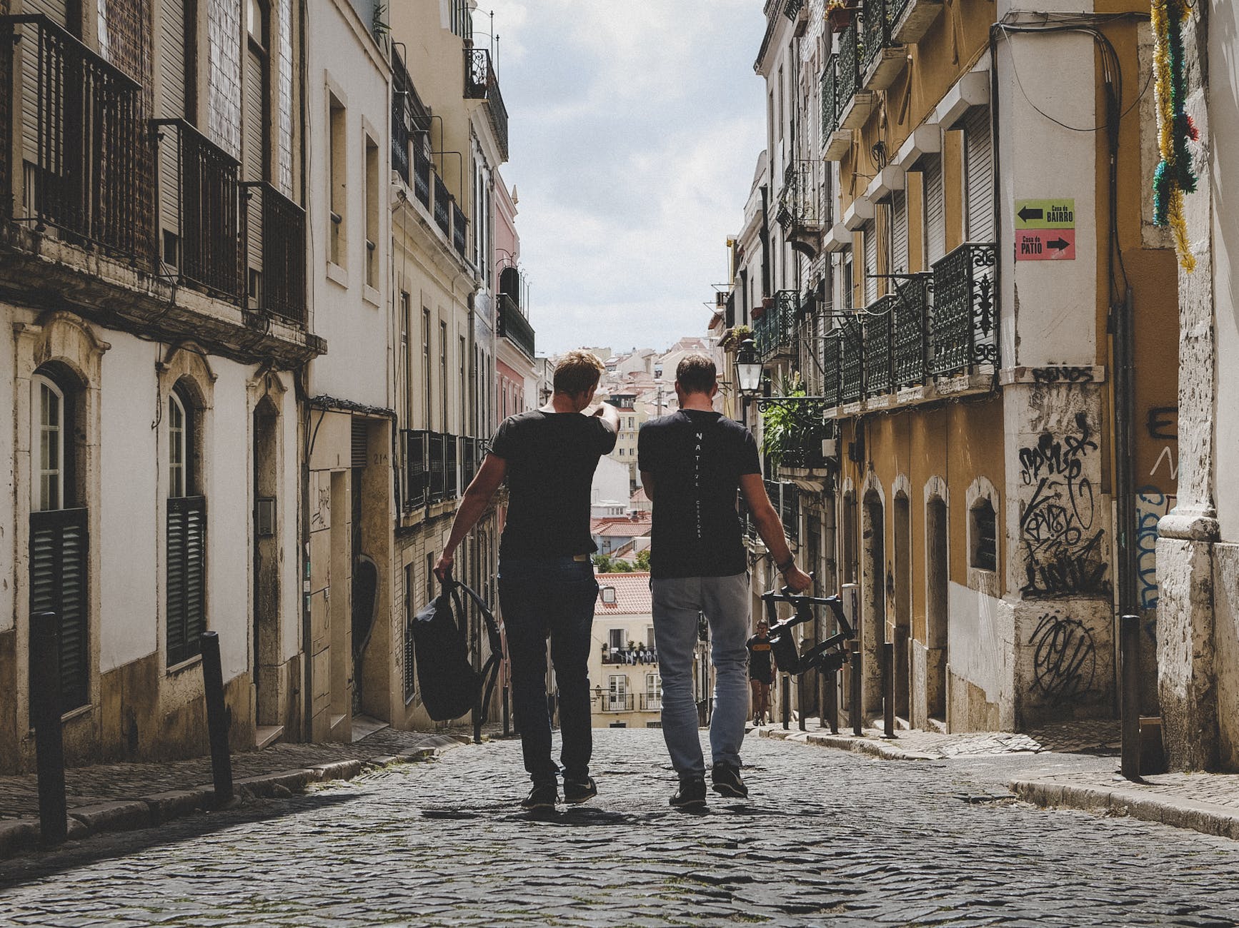 two man walking in between of buildings toward with concrete building