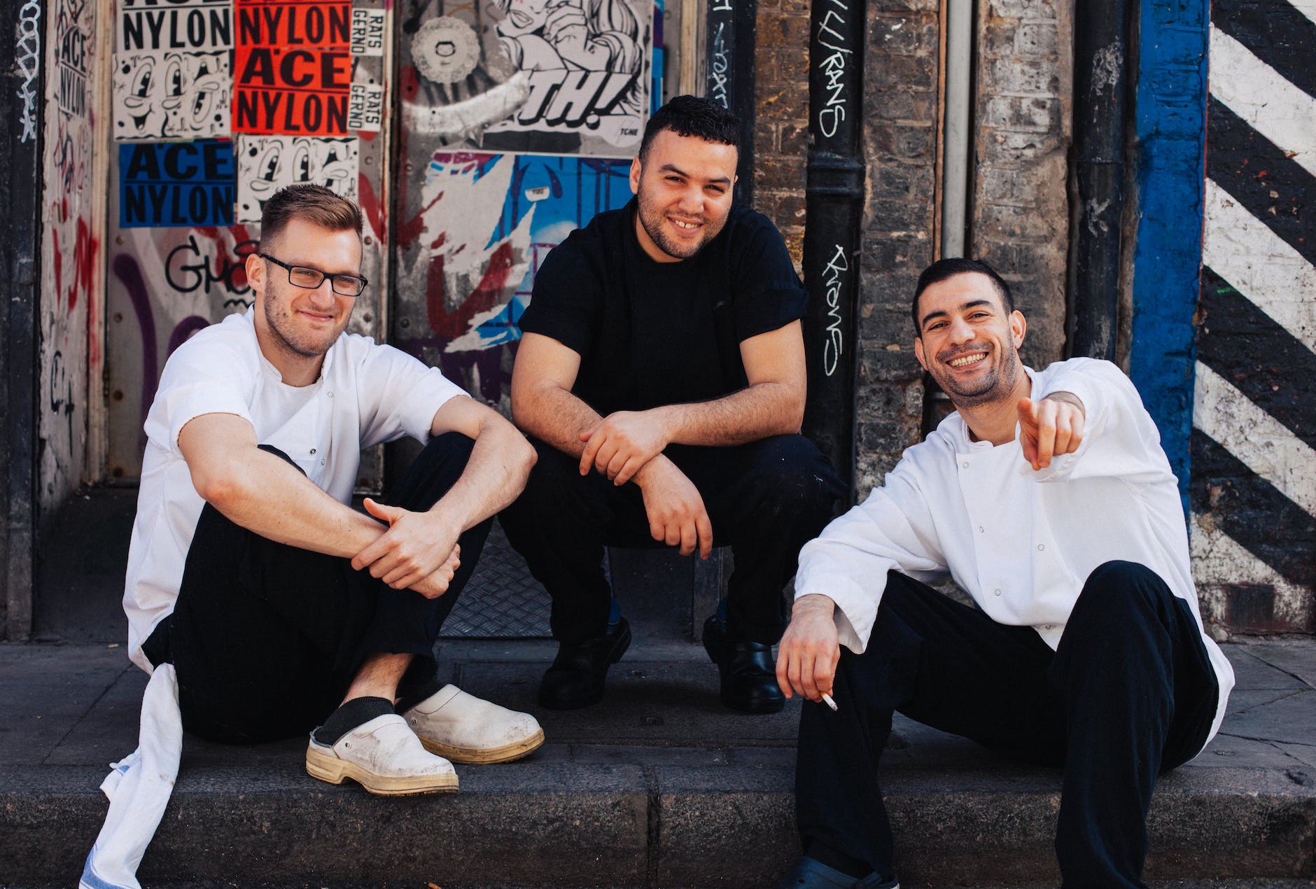 three men sitting on street curb